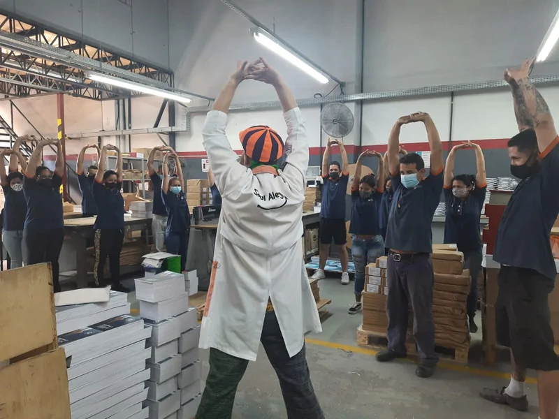 Palhaço do Soul Alegria conduzindo ginástica laboral com funcionários em uma fábrica